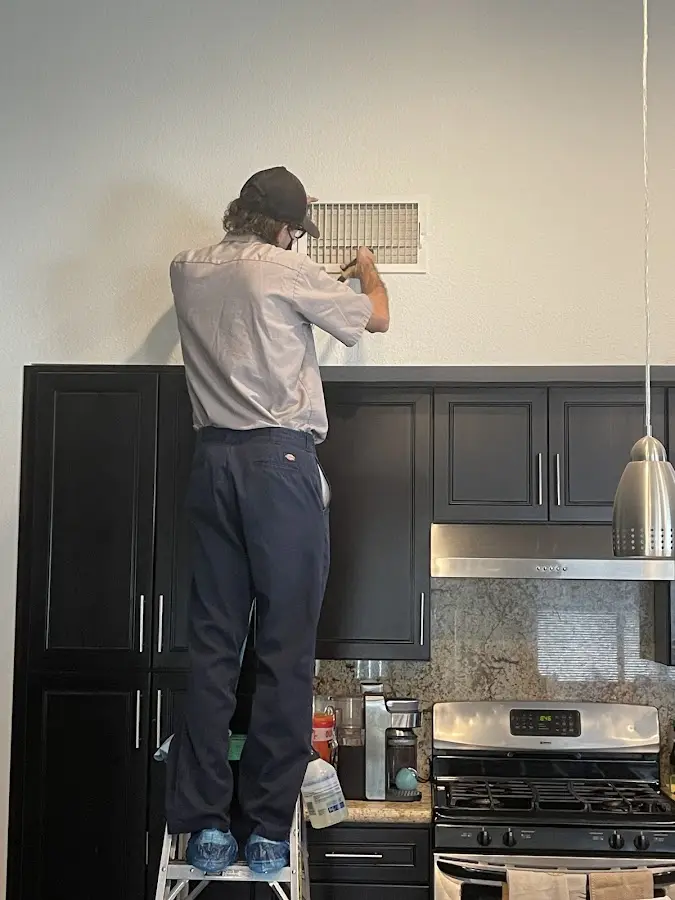 Technician inspecting an air vent during HVAC service in Leland